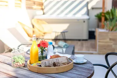 a table with a basket of food and a bottle of orange juice at L'entre deux-suite romantique - jacuzzi privatif - clim réversible - wifi in Le Somail