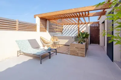 a patio with a wooden pergola and a table at L'entre deux-suite romantique - jacuzzi privatif - clim réversible - wifi in Le Somail