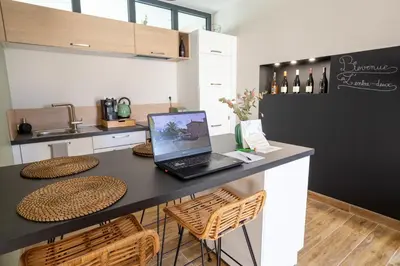 a kitchen with a table with a laptop on it at L'entre deux-suite romantique - jacuzzi privatif - clim réversible - wifi in Le Somail