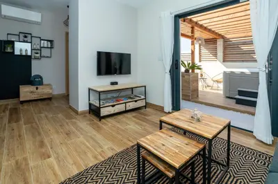 a living room with a television and wooden floors at L'entre deux-suite romantique - jacuzzi privatif - clim réversible - wifi in Le Somail