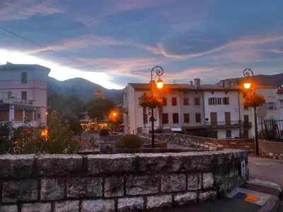 a city with buildings and a stone wall at dusk at Chateau View Chambres d'hôtes in Quillan