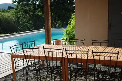 a wooden table with chairs and a pool at Domaine de 