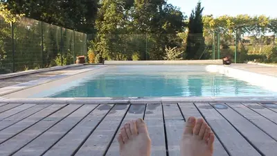 a person laying on a deck next to a swimming pool at Domaine de 