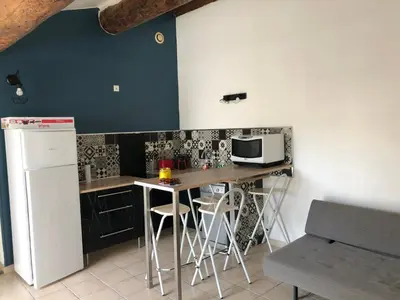 a kitchen with a table with stools and a microwave at Loft Toit Terrasse - Confort & Nature à Sigean in Sigean