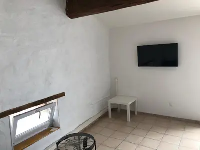 a room with a tv and a table and a window at Loft Toit Terrasse - Confort & Nature à Sigean in Sigean