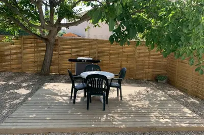 a patio with a table and chairs and a fence at Location studio entre garrigue et mer in Vinassan