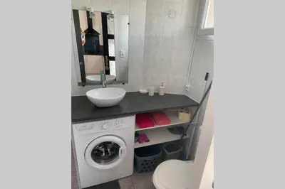 a bathroom with a washing machine and a sink at Location studio entre garrigue et mer in Vinassan