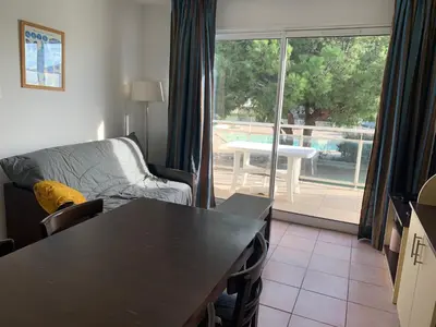 a living room with a couch and a table and a view of a patio at T2 Les jardins Gruissan in Gruissan