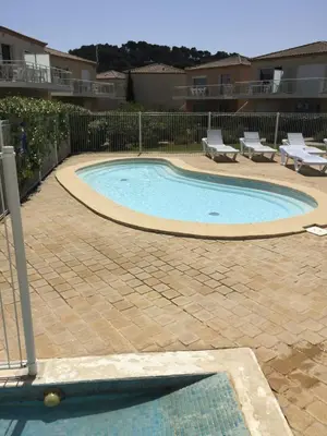 a small swimming pool in a yard with two lounge chairs at T2 Les jardins Gruissan in Gruissan