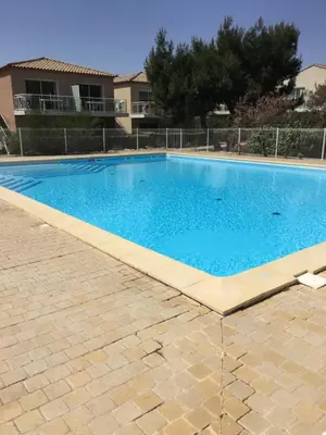 a large blue swimming pool in front of a house at T2 Les jardins Gruissan in Gruissan