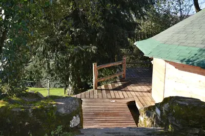 a wooden deck with a wooden gate and a building at Les Ecuries de la Sabatarié in Cambounès