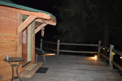 a wooden cabin with a chair and a table on a deck at Les Ecuries de la Sabatarié in Cambounès