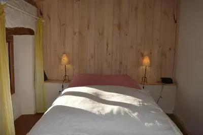 a bedroom with a bed with two lamps on it at Les Ecuries de la Sabatarié in Cambounès