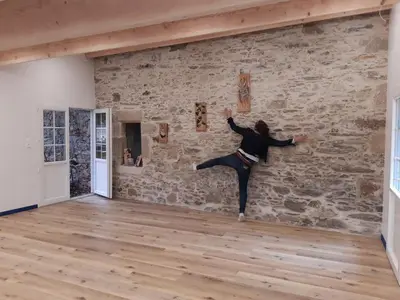 a woman dancing in a room with a stone wall at Les Ecuries de la Sabatarié in Cambounès