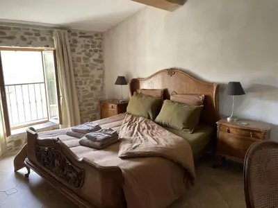 a bedroom with a large wooden bed with two night stands at Le Domaine de La Tuilerie - Gite de charme en bord de riviere avec piscine in Serviès-en-Val