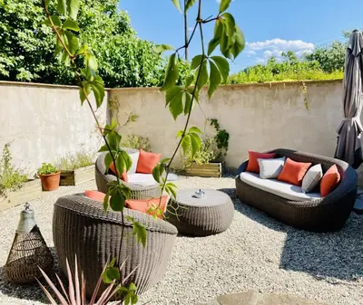 a patio with two wicker chairs and a couch at Le Domaine de La Tuilerie - Gite de charme en bord de riviere avec piscine in Serviès-en-Val