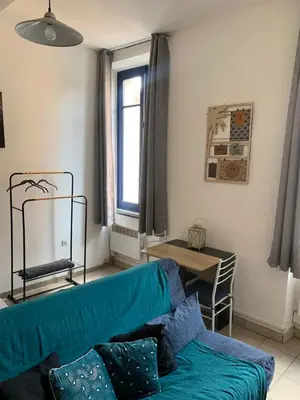 a living room with a blue couch and a window at Studio en plein centre in Carcassonne