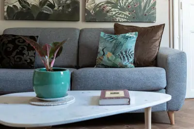 a living room with a couch and a table with a plant at Maison d'hôtes ÔVillage in Ouveillan
