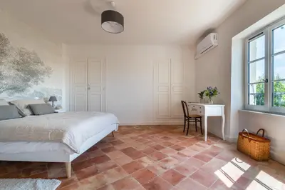 a bedroom with a bed and a desk and a window at Maison d'hôtes ÔVillage in Ouveillan