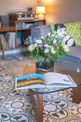 an open book on a table with a vase of flowers at Maison d'hôtes ÔVillage in Ouveillan