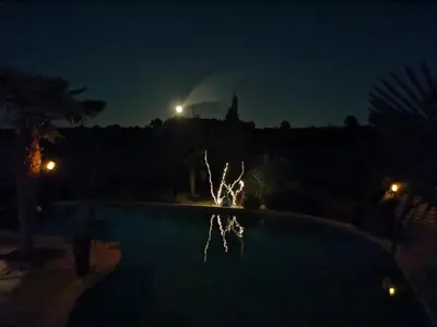 a nightime view of a swimming pool with a building in the background at Studio Camille in Sainte-Vallière
