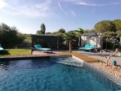 a swimming pool in a yard with two blue chairs at Studio Camille in Sainte-Vallière