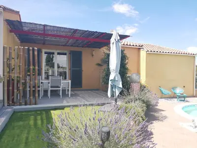 a patio with an umbrella and a table and a pool at Studio Camille in Sainte-Vallière