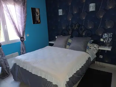 a bedroom with a large bed with blue walls at Cher Micheée et Bernard in Camplong-dʼAude