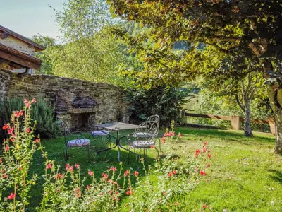 a table and chairs in a yard next to a stone wall at Gite des Kathares in Montferrier