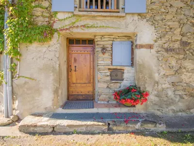 a stone building with a wooden door and a bunch of flowers at Gite des Kathares in Montferrier