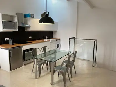 a kitchen with a glass table and chairs in it at La maison Barberousse in Gruissan