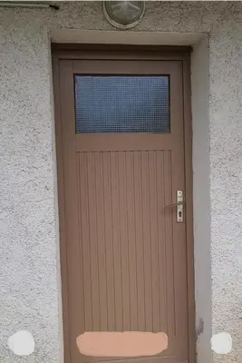a brown door with a window on a building at Studio meublé Viane in Viane