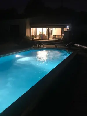 a swimming pool at night with a table in the background at VILLA LOUNA 4 étoiles in Ventenac-Cabardès