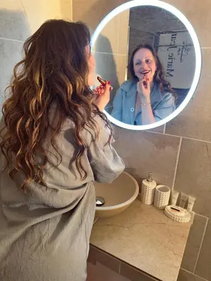 a woman brushing her teeth in front of a bathroom mirror at Marie Jean Chambre d'hôtes & Gîte in Oupia
