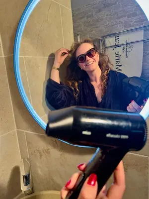 a woman is drying her hair in front of a mirror at Marie Jean Chambre d'hôtes & Gîte in Oupia