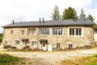 an old stone house with a black roof at GITE AUTOMNE in Le Soulié