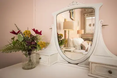 a vase of flowers on a table in front of a mirror at Carcassonne Bed and Breakfast du Palais in Carcassonne