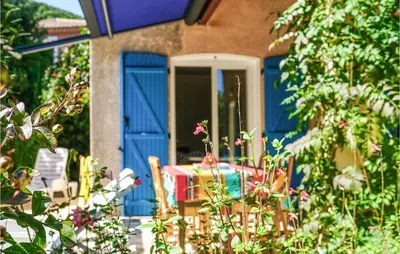 a table and chairs in front of a house with blue doors at 2 Bedroom Awesome Home In Berlou in Berlou