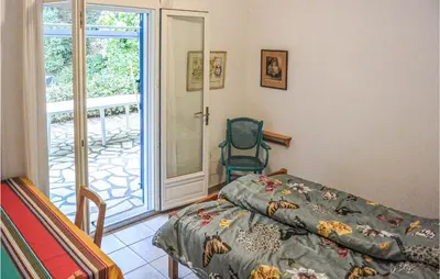 a bedroom with a bed and a chair and a sliding glass door at 2 Bedroom Awesome Home In Berlou in Berlou