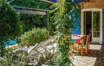 a patio with a table and chairs and ivy at 2 Bedroom Awesome Home In Berlou in Berlou