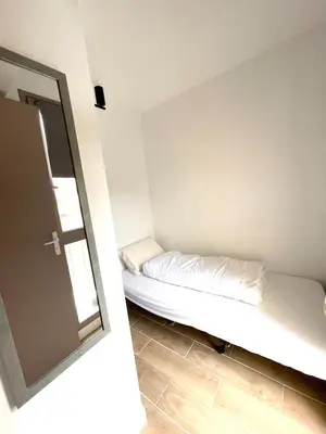 a small room with a bed and a mirror at Studio Plage du Grazel in Gruissan