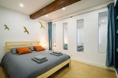 a bedroom with a large bed in a room with windows at Superbe appartement plein centre, calme, Netflix in Mirepoix