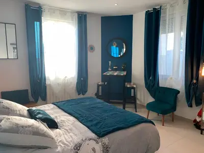 a bedroom with blue curtains and a bed and a chair at La Liberté in Narbonne
