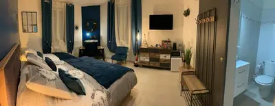 a bedroom with a large bed and a bathroom at La Liberté in Narbonne