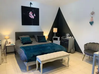 a bedroom with a large bed and a chair at La Kloé in Narbonne
