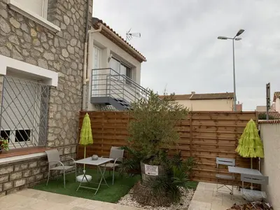 a patio with a table and chairs and a fence at La Kloé in Narbonne