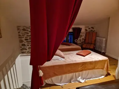 a bedroom with a bed with a red curtain at Charmante petite grange - 5 Couchages in Nalzen