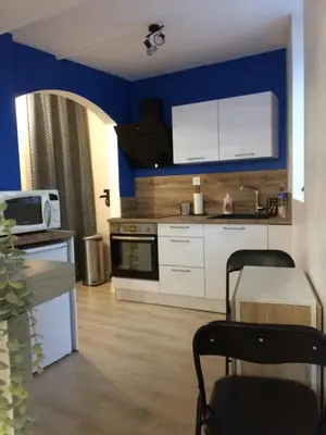 a kitchen with white cabinets and a blue wall at Le Montréalais in Montréal