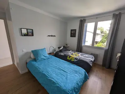 a bedroom with two beds and a window at L'esplanade, appartement en centre-ville au calme in Puisserguier