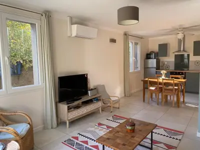 a living room with a television and a dining room at L'esplanade, appartement en centre-ville au calme in Puisserguier